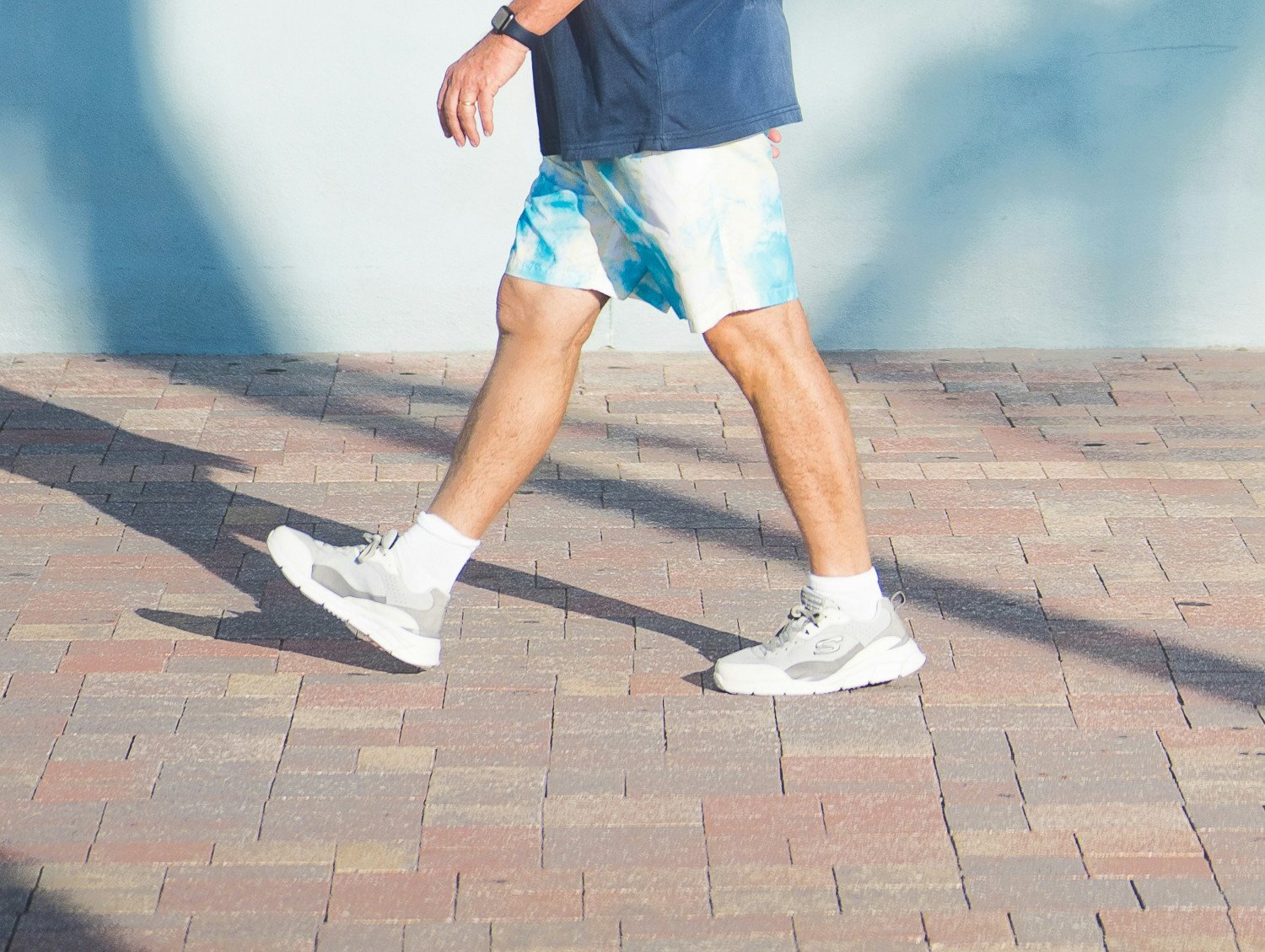 Man som går med ett steg från sidan, fokus på benen